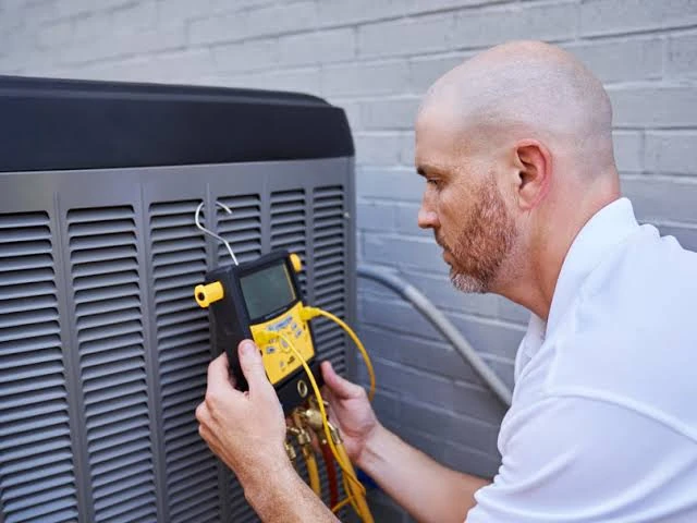 Technician using a digital diagnostic meter to inspect an outdoor HVAC unit