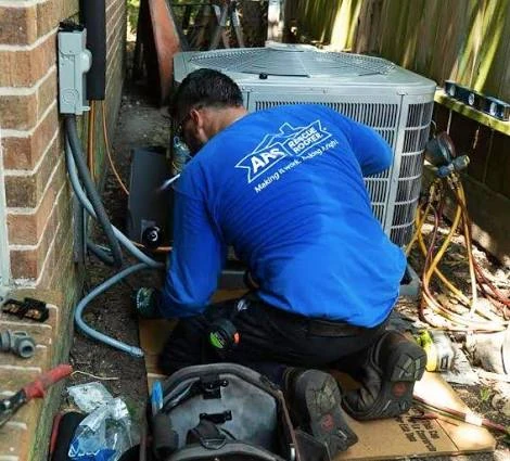 Technician repairing an outdoor air conditioning unit beside a brick home